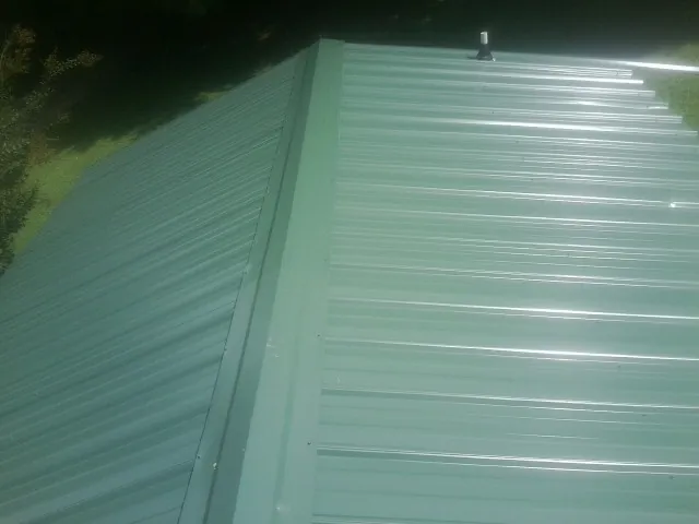 New green metal panels meeting at the ridge of a roof — Flat Roof Repair work by our crew in Brush Prairie