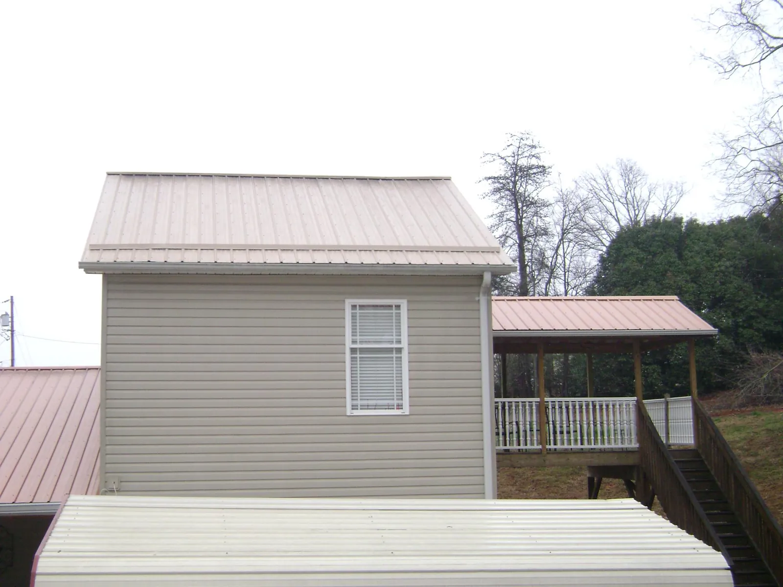 Tan metal roofs on a two story addition and attached porch, from a Roof Replacement job in Brush Prairie