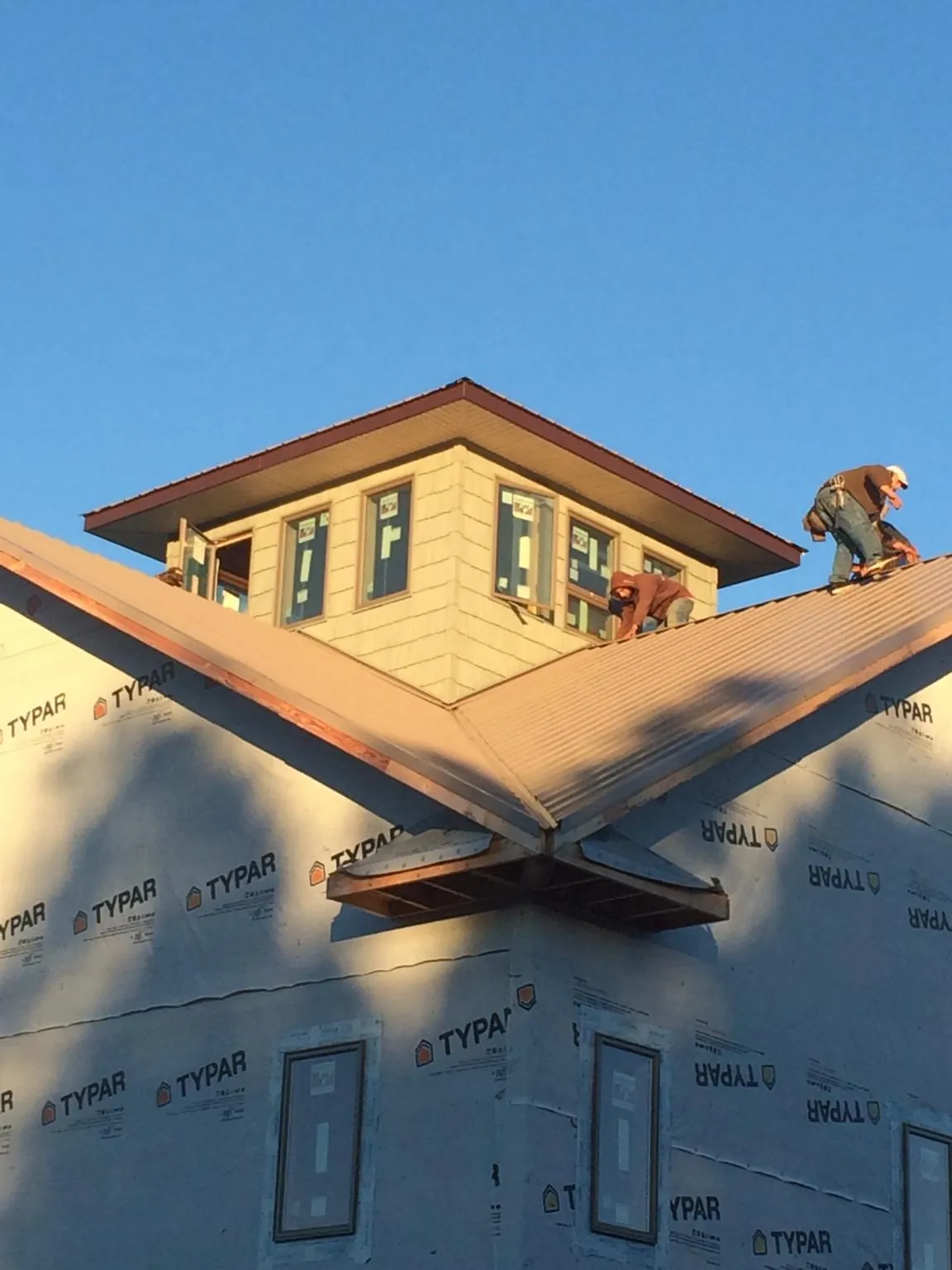Roofers working around a rooftop cupola on a new metal roof at sunset — Roof Waterproofing in Brush Prairie by Roofing Brothers